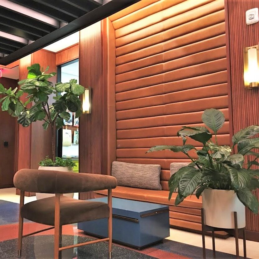 Cozy modern seating area with wooden wall and green plants.