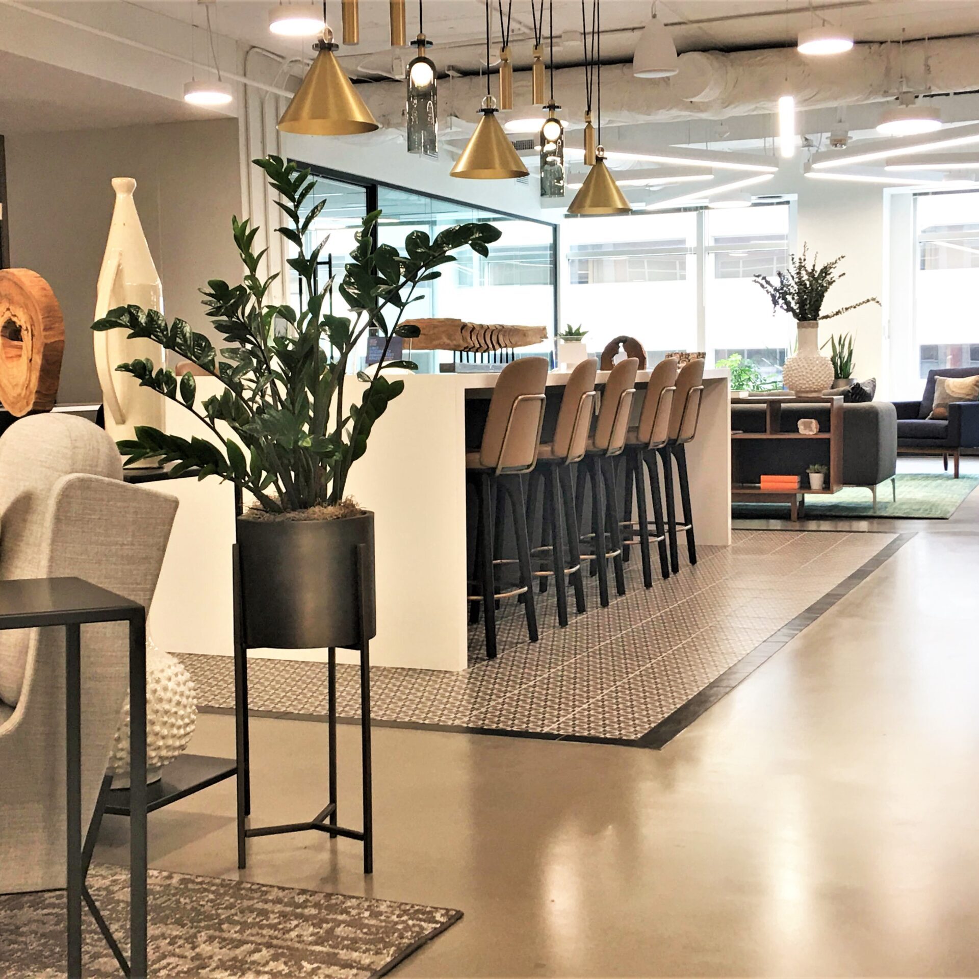 Modern office lounge with bar seating and plants.